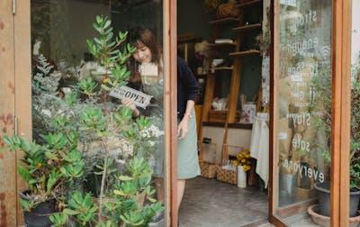 Asian florist turning a signboard on a store wall